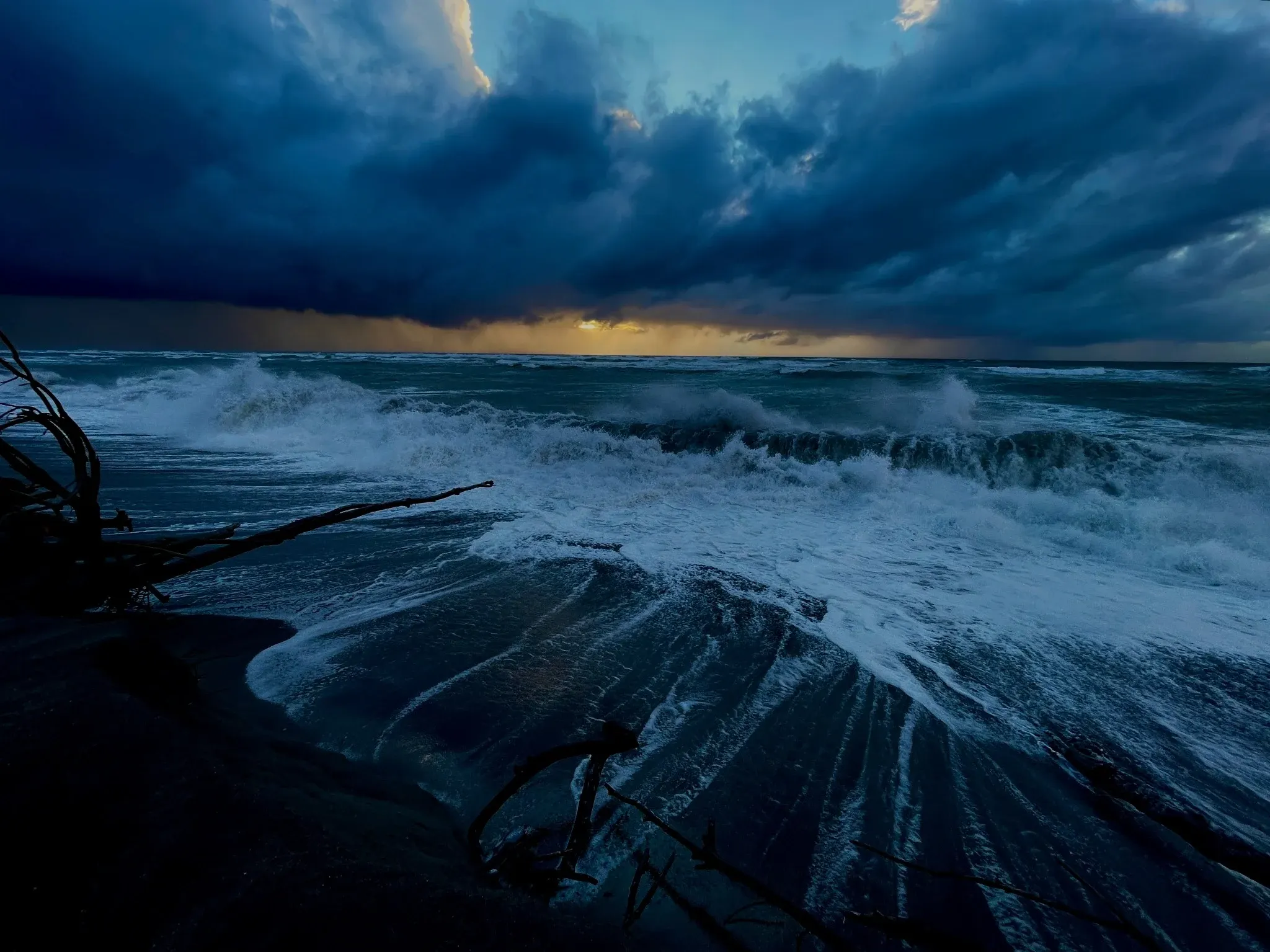 Surf breaking under a heavy sky on the Tasman coast at dusk
